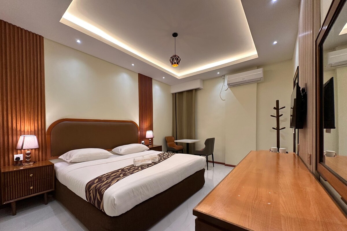 Une chambre d’hôtel moderne avec un grand lit, des tables de chevet, un bureau et une chaise.