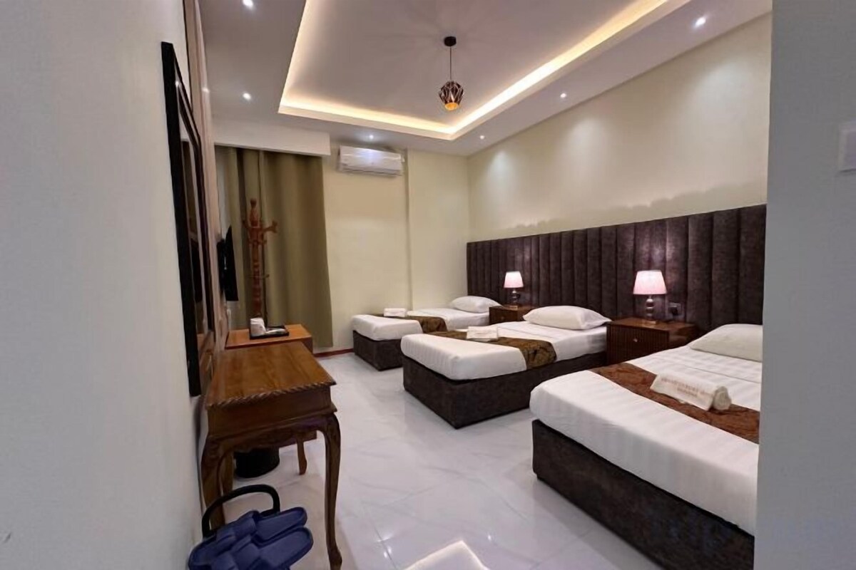 Una habitación de hotel con cama, mesita de noche, lámpara y espejo.