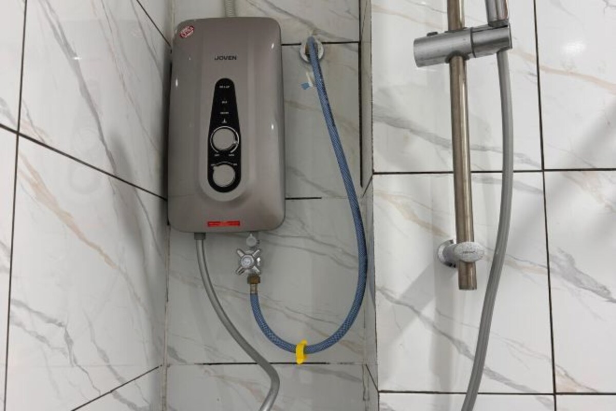 A shower control panel with a hose, a handheld showerhead, and a wall-mounted faucet.