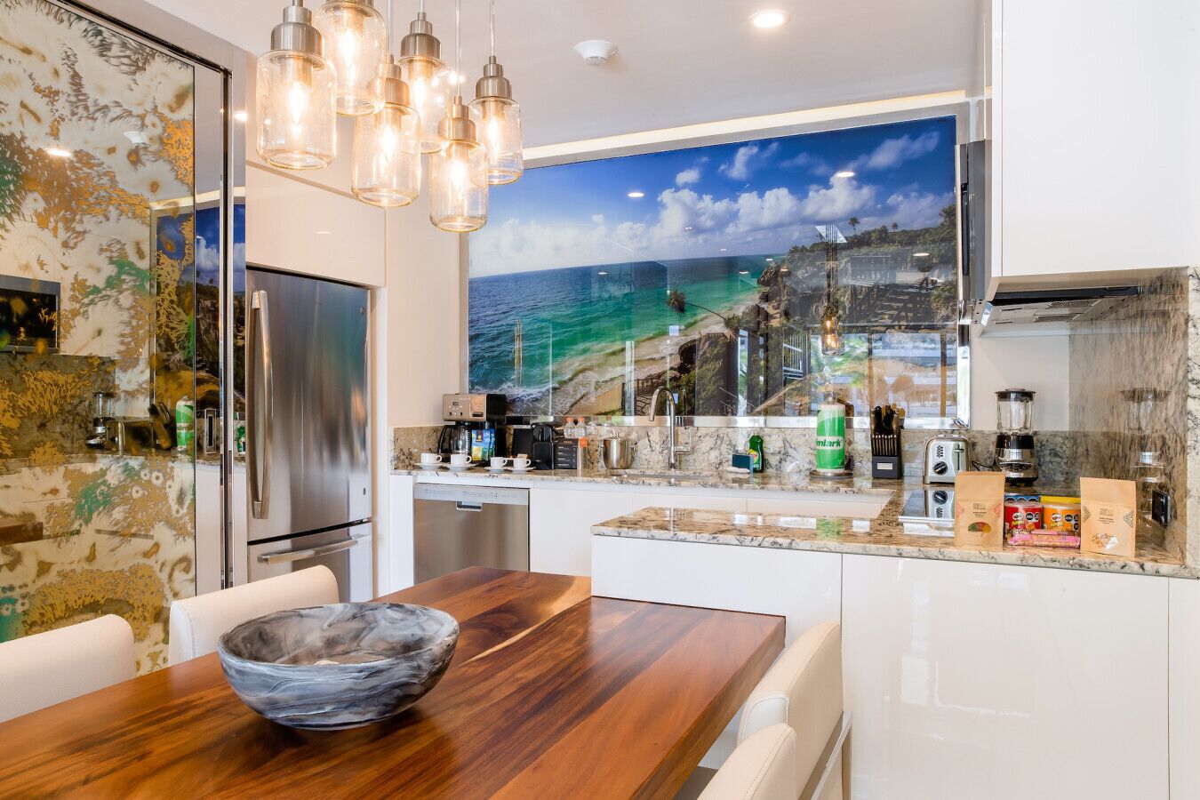 A modern kitchen with a large island, stainless steel appliances, and a scenic ocean view mural.