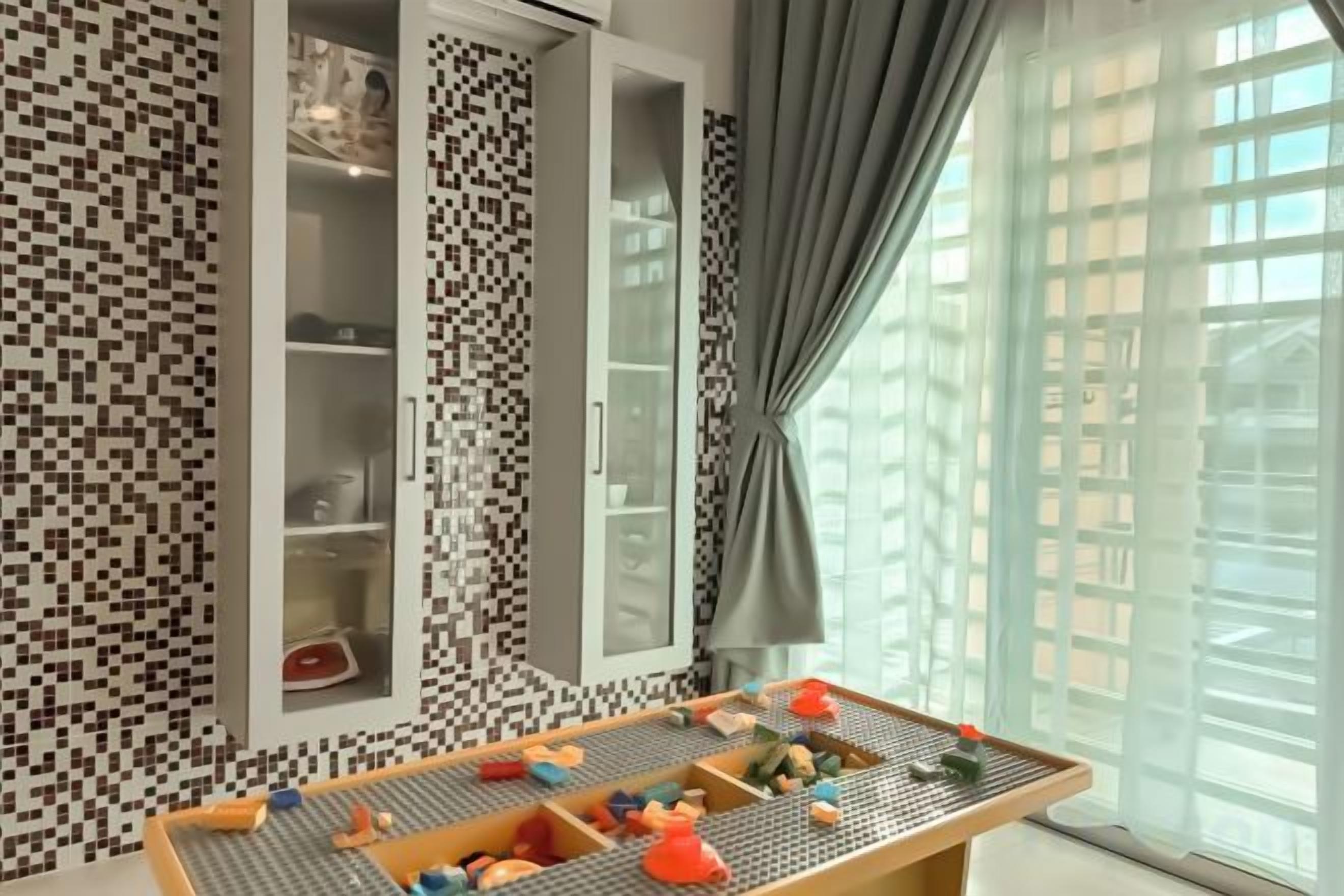 Quarto com piso xadrez, uma mesa com brinquedos e janela com cortinas.