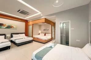 Une chambre d’hôtel avec deux lits, un coin salon et une salle de bain dotée d’une porte en verre.
