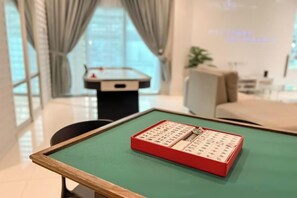 Une pièce avec une table verte, une boîte rouge ornée de caractères chinois, un baby-foot et un canapé.
