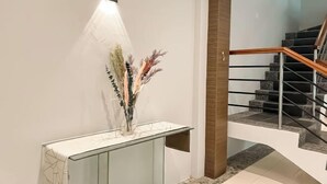 Una escalera moderna con barandilla de vidrio y una pared blanca con una lámpara.