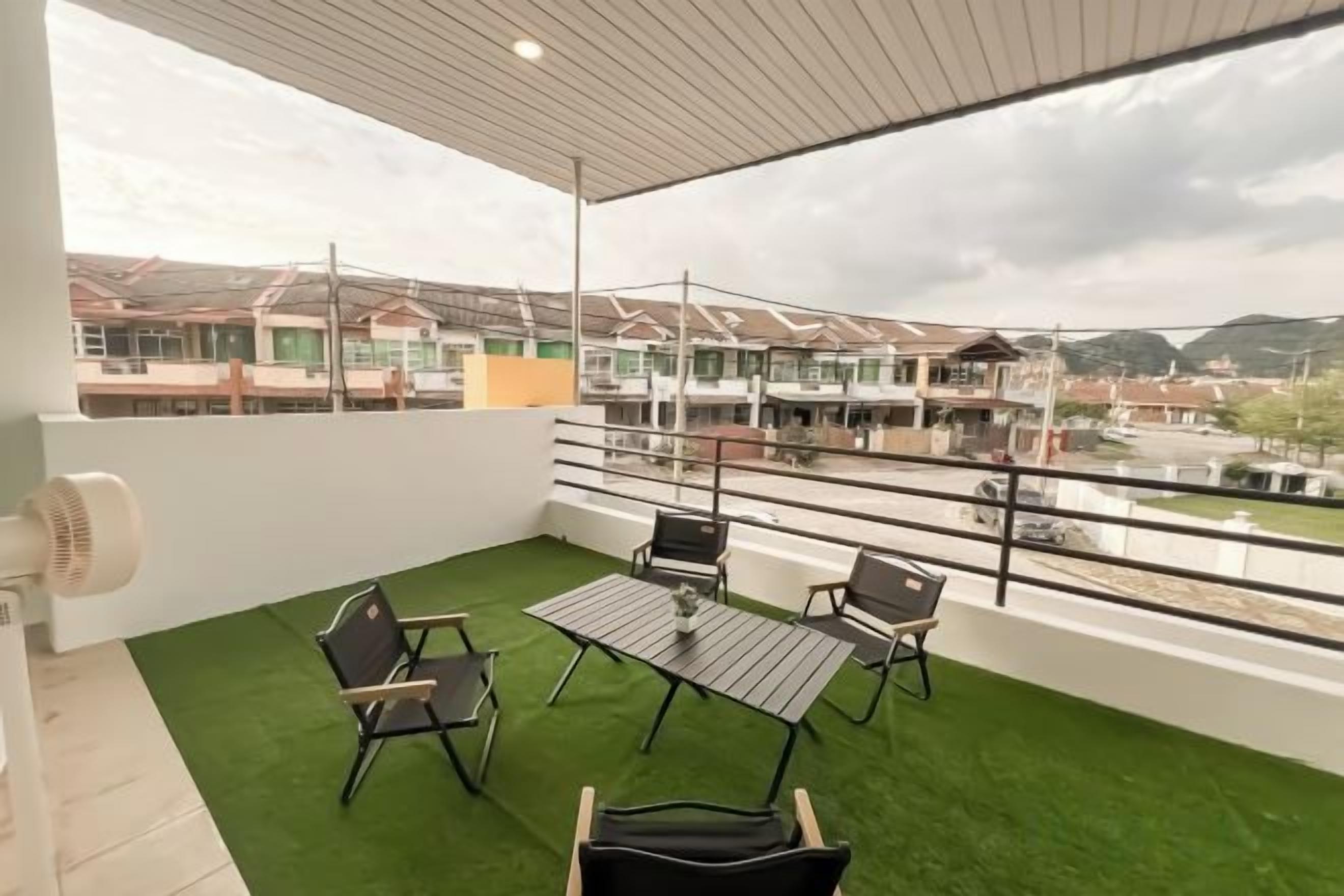 A balcony with a table and chairs, a fan, and a view of buildings and a river.