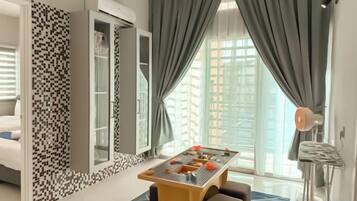 A hotel room with a dining table, a sofa, a patterned wall, and a view through a window.