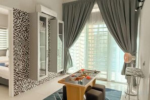 Una habitación de hotel con una mesa de comedor, un sofá, una pared con diseño y vistas a través de una ventana.