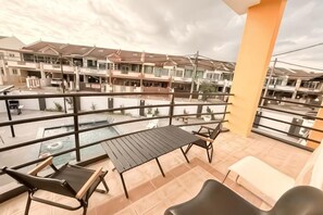 Un balcon avec une piscine, du mobilier d’extérieur et une vue sur un quartier résidentiel.