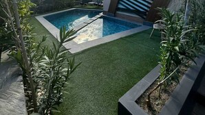 A modern building with a swimming pool, surrounded by artificial grass and plants. - La villa luxury suites (Marrakech)