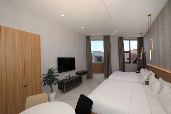 A modern hotel room with a large bed, a TV, a desk, and a potted plant. - La villa luxury suites (Marrakech)