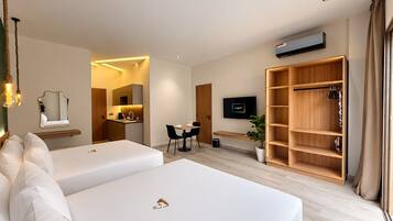 Een hotelkamer met twee bedden, een bureau, een televisie, een kledingkast en een badkamer.