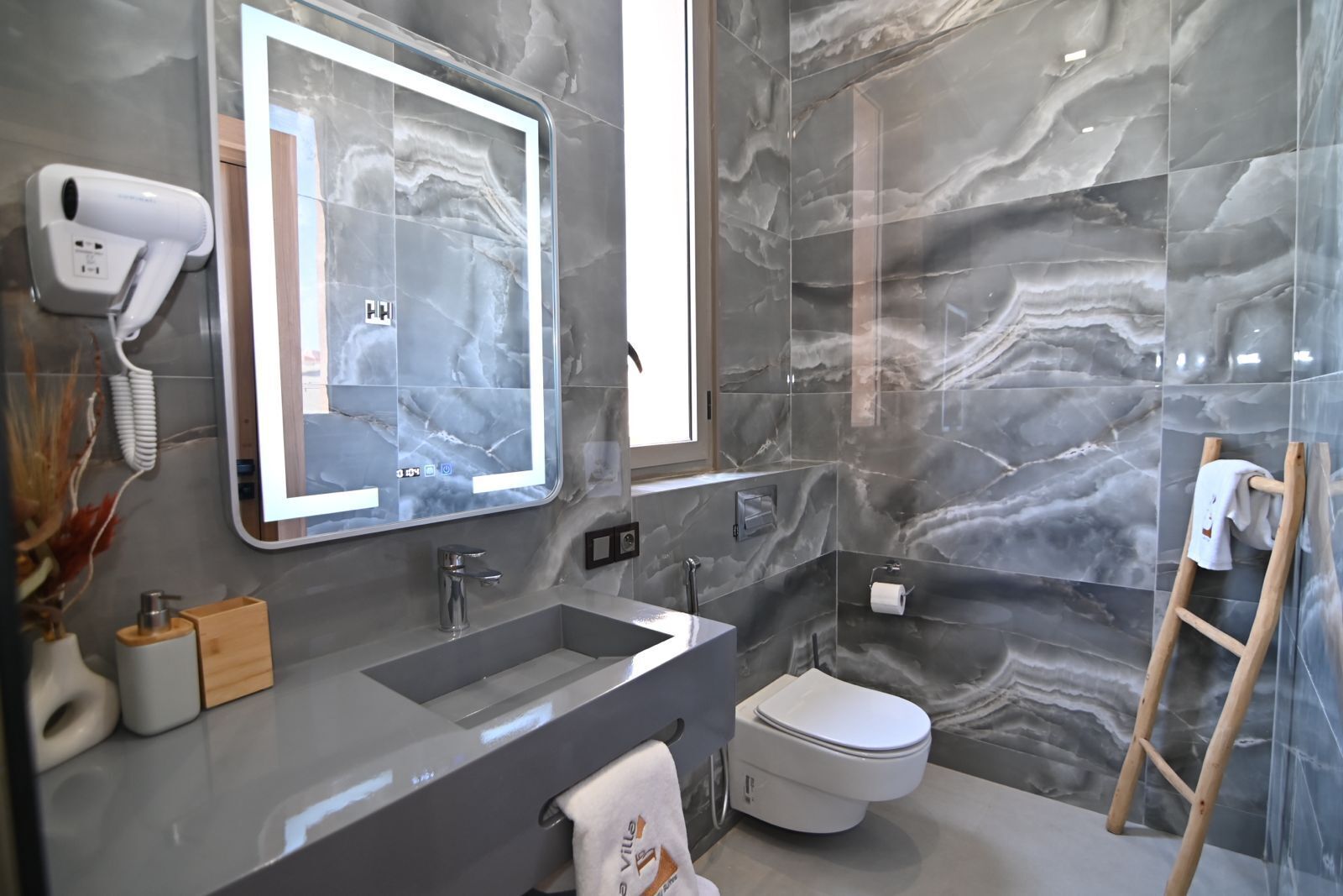 A modern bathroom with a large mirror, a sink, a toilet, and a shower area.
