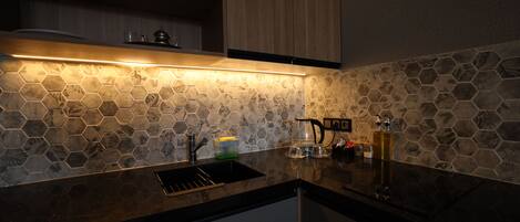 Una cocina moderna con salpicadero de azulejos hexagonales, encimera negra y armarios de madera.