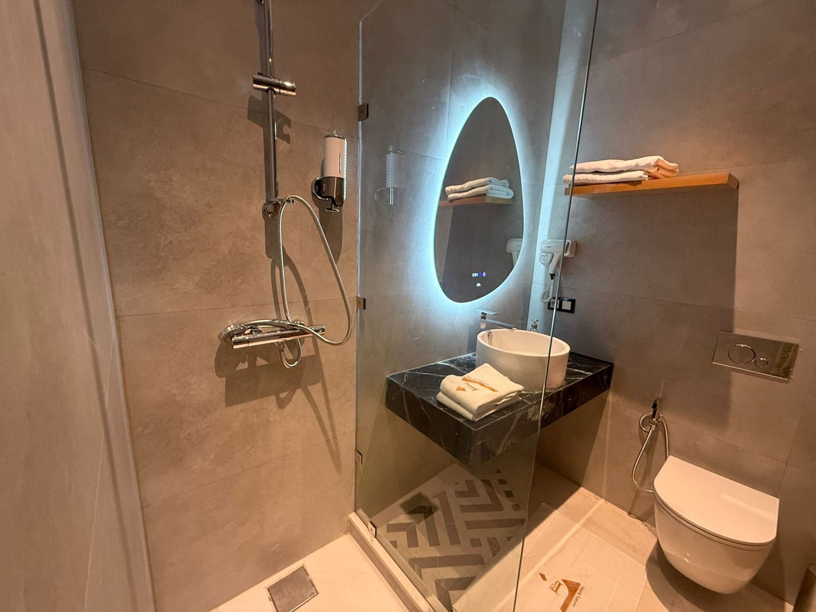 A modern bathroom with a glass-enclosed shower, a vanity with a sink, and a toilet.