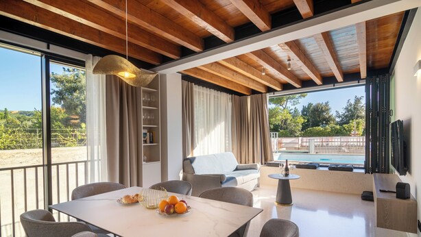 Una sala de estar moderna con comedor, ventanas amplias y vista a la piscina.