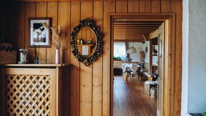 A wooden interior with a mirror, framed picture, and a louvered door leading to a dining area. - Garni Cir (Santa Cristina Val Gardena)