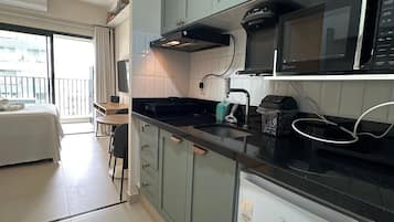 Studio | Privékeuken | Een koelkast, een magnetron, een kookplaat, kookgerei, borden en bestek