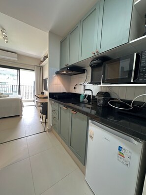 A compact kitchen with a microwave, a small refrigerator, and a dining area with a table and chairs.