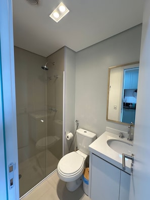 Ein modernes Badezimmer mit einer Duschkabine, einer Toilette und einem Waschbecken mit Spiegel.