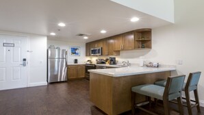 Une cuisine moderne avec des meubles en bois, des appareils électroménagers en acier inoxydable et un îlot central doté de tabourets de bar.