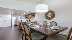 Un coin repas avec une table en bois dressée pour quatre personnes, entourée de chaises dotées d’assises rembourrées. Un grand miroir est accroché au mur, au-dessus de la table.