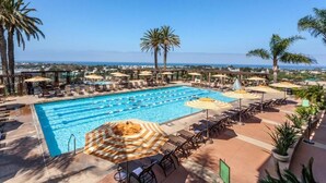 Une piscine avec plusieurs couloirs de nage, des chaises longues, des parasols et des palmiers.