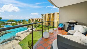 A balcony with a view of a swimming pool, a lawn, and a building in the background. - Oceania 343 J.e. Irausquin Blvd 238 (Oranjestad)
