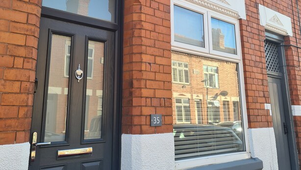 A red brick house with a black front door, white window frames, and a small balcony. - Quaint 2-bedroom house in Leicester for a cozy getaway (Leicester)