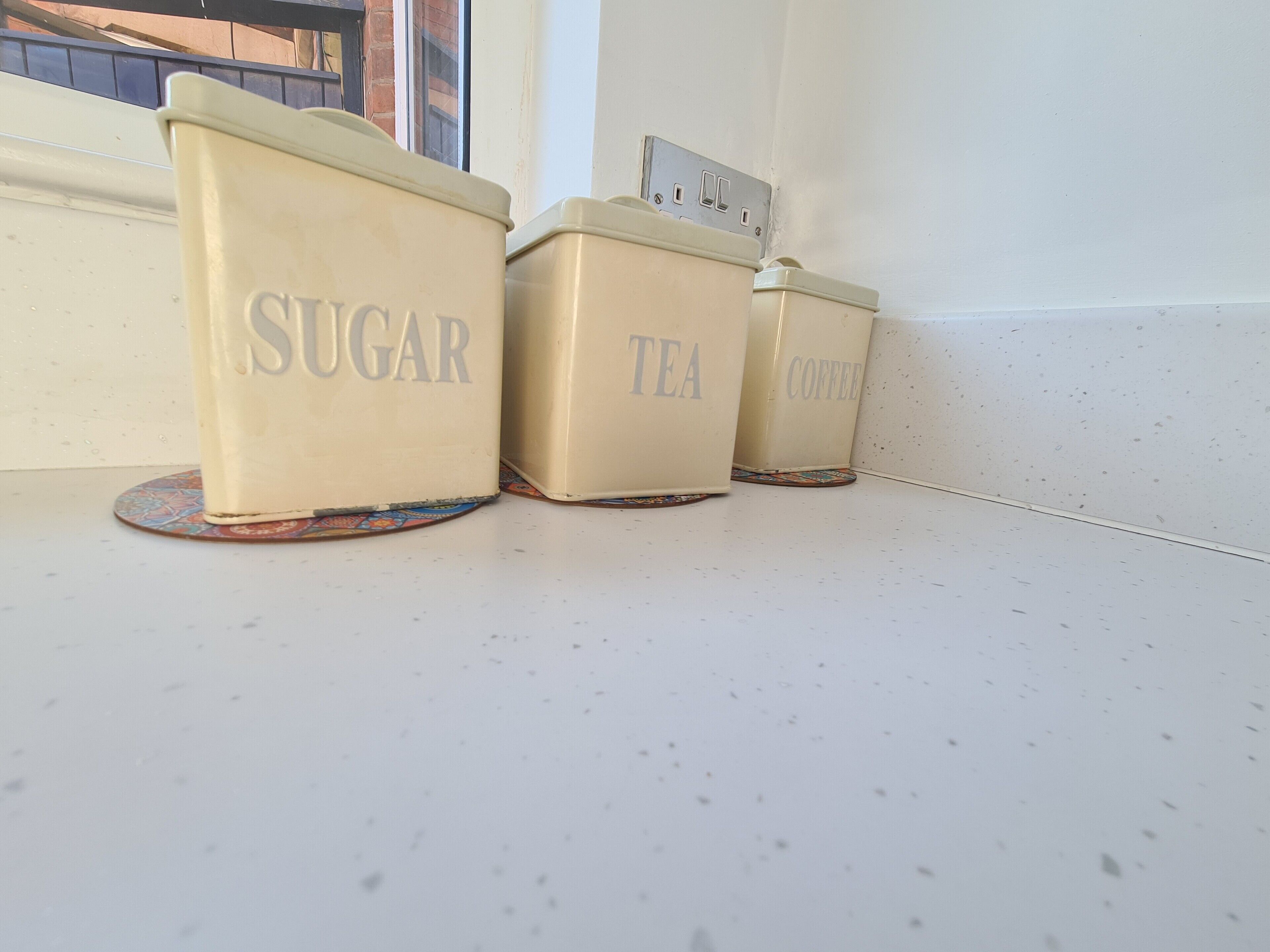 Three vintage-style containers labeled 'SUGAR', 'TEA', and 'COFFEE' on a kitchen counter.