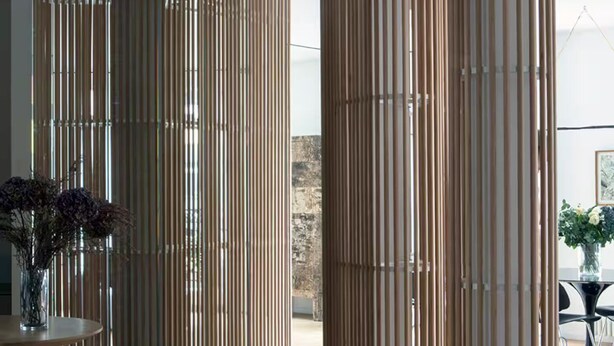 Un interior moderno con un panel de vidrio, listones de madera y suelo de madera.