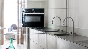 Una cocina moderna con encimera de acero inoxidable, horno empotrado y pileta doble.
