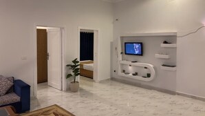 Una sala de estar moderna con un televisor montado en la pared, un ventilador de techo y una planta en maceta.