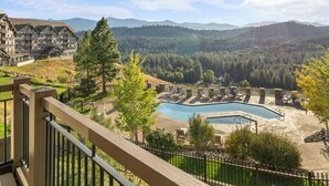 A resort with a large pool, outdoor seating, and a mountainous backdrop. - Tranquil Suncadia Lodge with Fireplace, Mountain Views and Pool Hot Tub (Cle Elum)