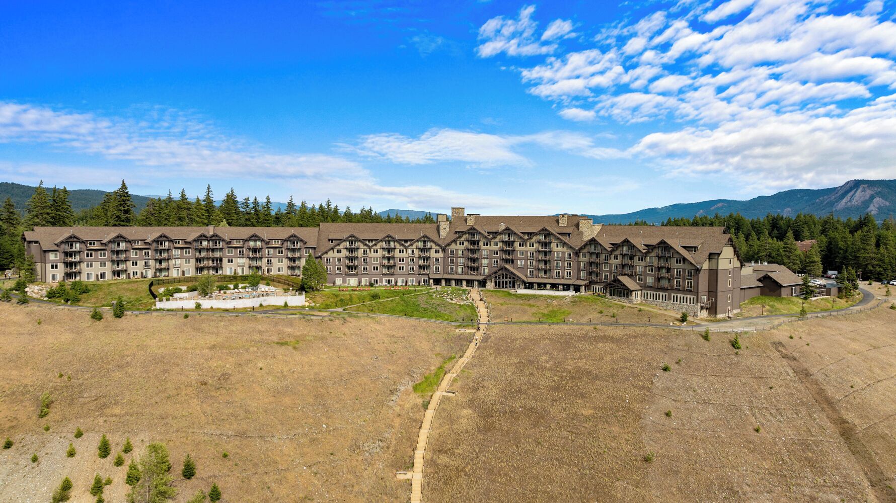 A large hotel with multiple buildings, a central courtyard, and a mountainous backdrop.