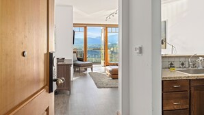 A spacious living area with a large window, a wooden door, and a kitchen with a sink and countertop. - Tranquil Suncadia Lodge with Fireplace, Mountain Views and Pool Hot Tub (Cle Elum)