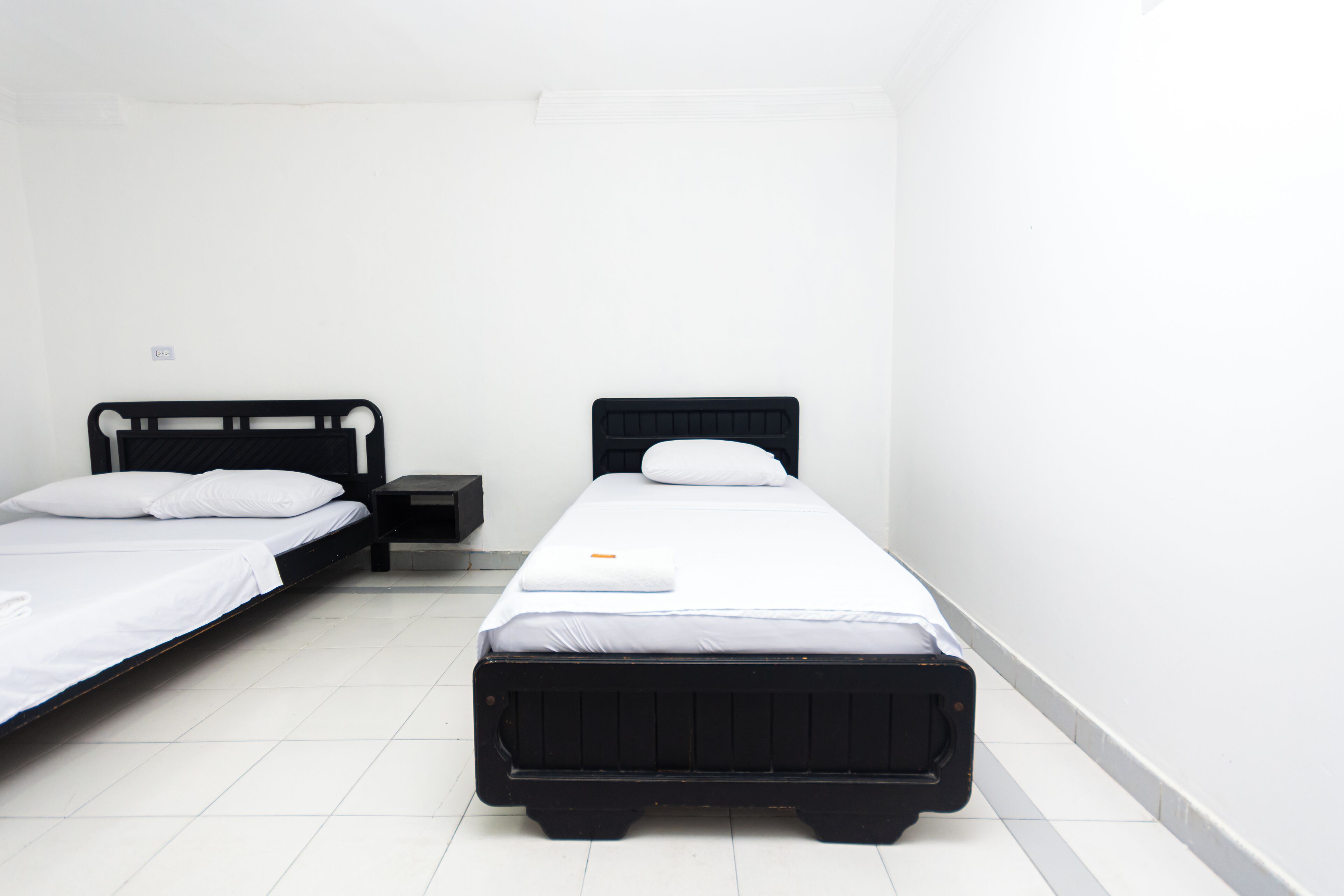 Una habitación con dos camas individuales, una mesita y una mesilla de noche.