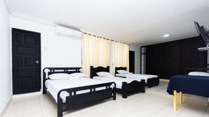 A hotel room with three single beds, a desk with a table, and a black wardrobe. - COSTA CARIBE BAQ HOTEL (Barranquilla)