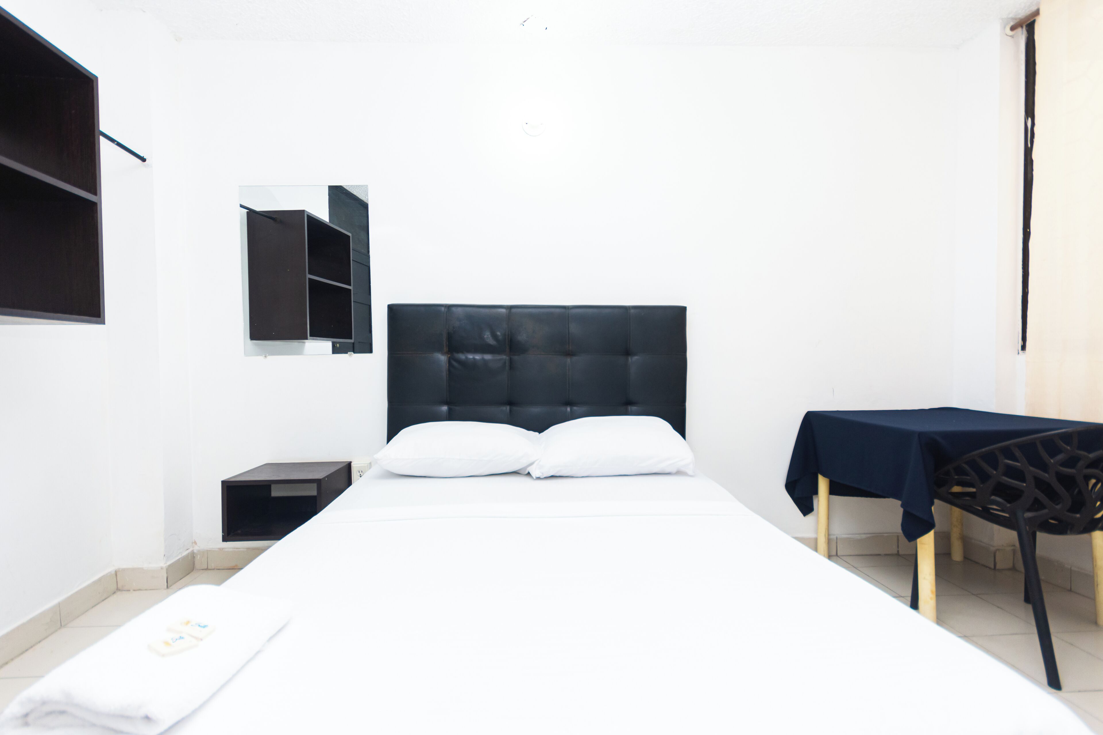 Un dormitorio con cama, mesita de noche, silla y mesa.