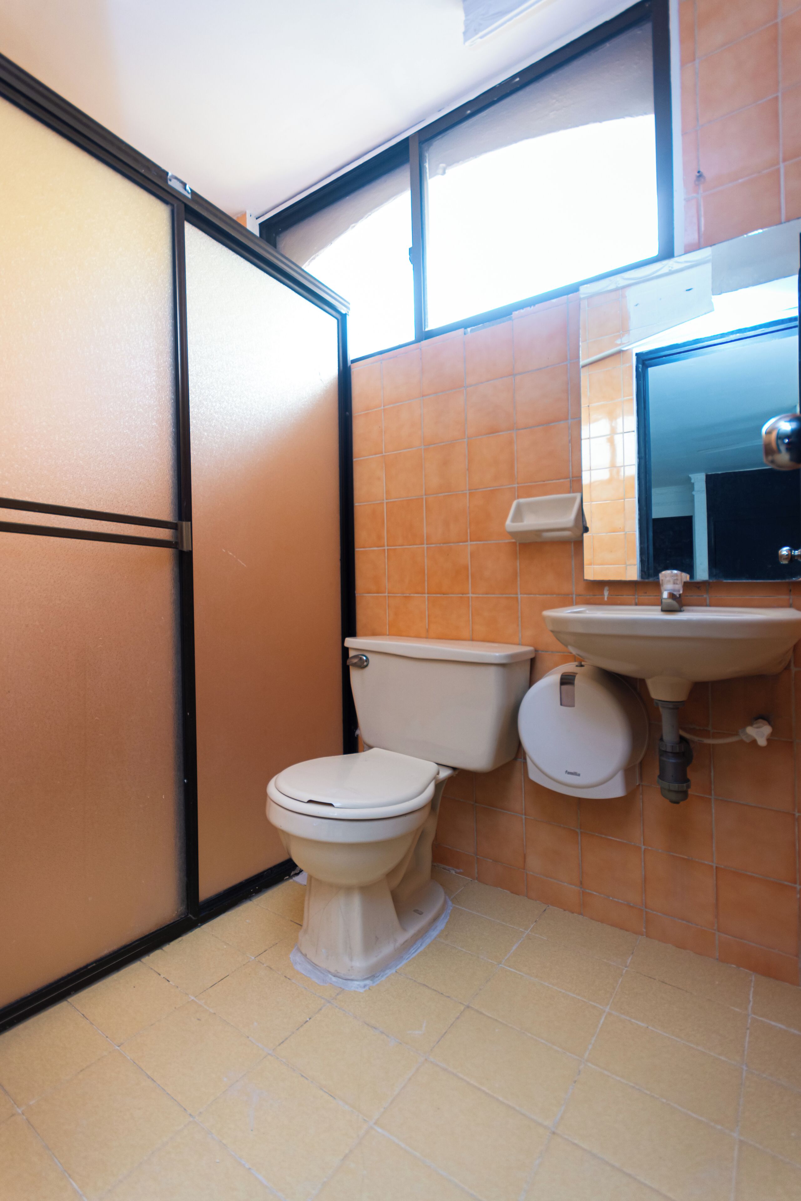 A small bathroom with a toilet, sink, and mirror.