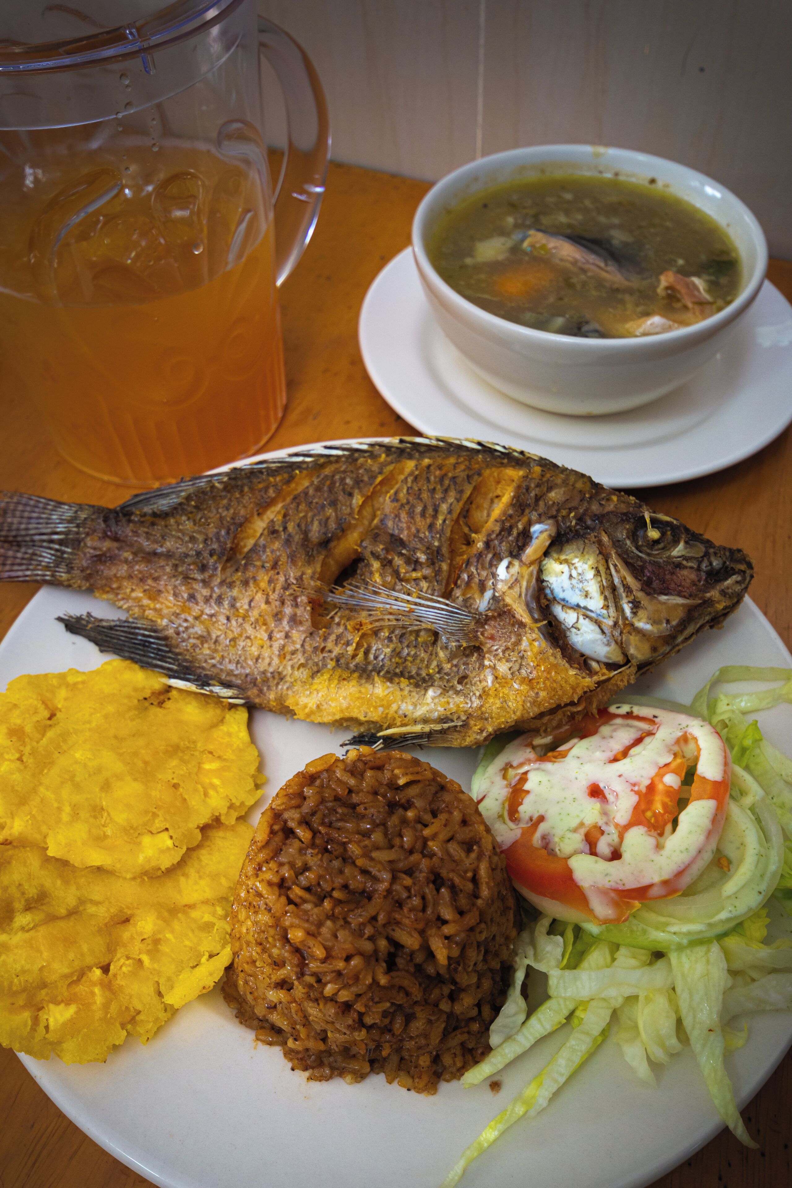 Une assiette avec un poisson entier, du riz et un bol de soupe.