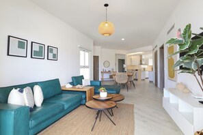 Un salon moderne avec un canapé de couleur turquoise, une table basse en bois et un luminaire suspendu.