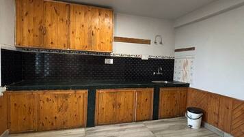 A kitchen with wooden cabinets, a black backsplash, and a light-colored floor.