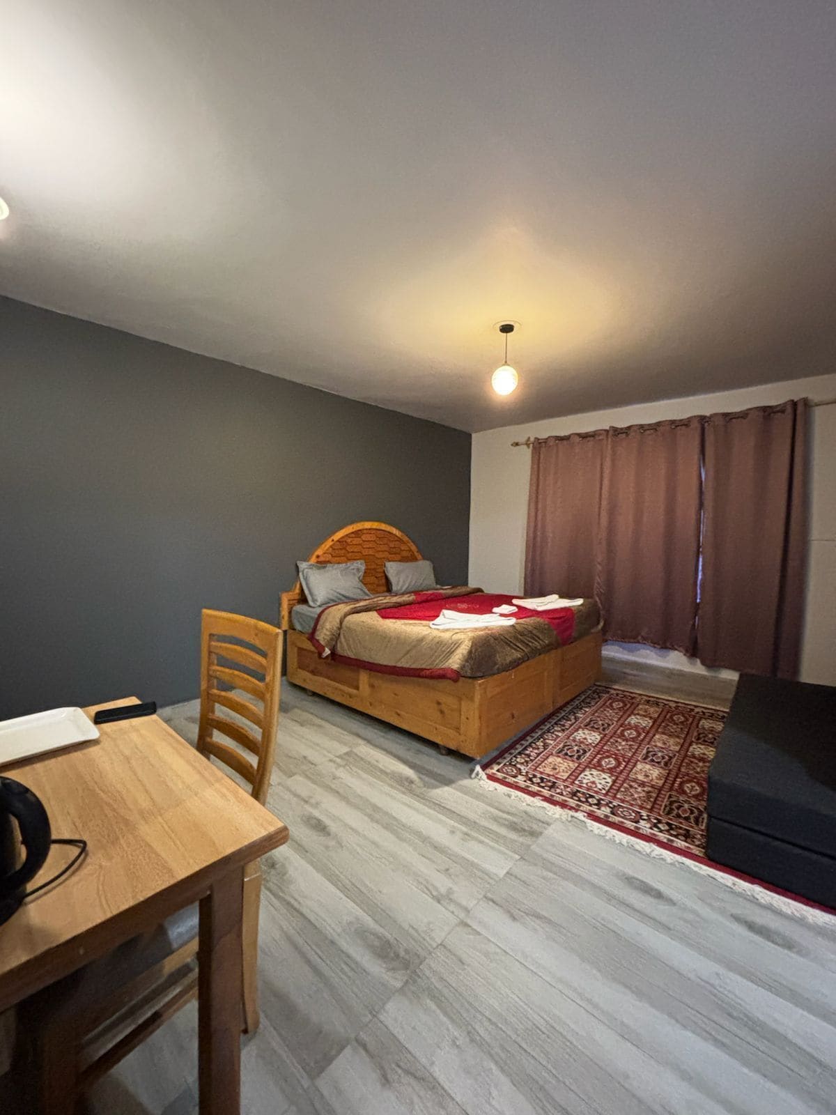 A bedroom with a wooden bed, a small table, and a chair.