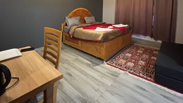 A bedroom with a wooden bed, a small table, and a chair.