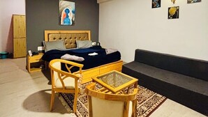 A modern bedroom with a bed, a wooden chair, a glass coffee table, and a sofa. - Holidays in Haven Hospitality  (Manali)