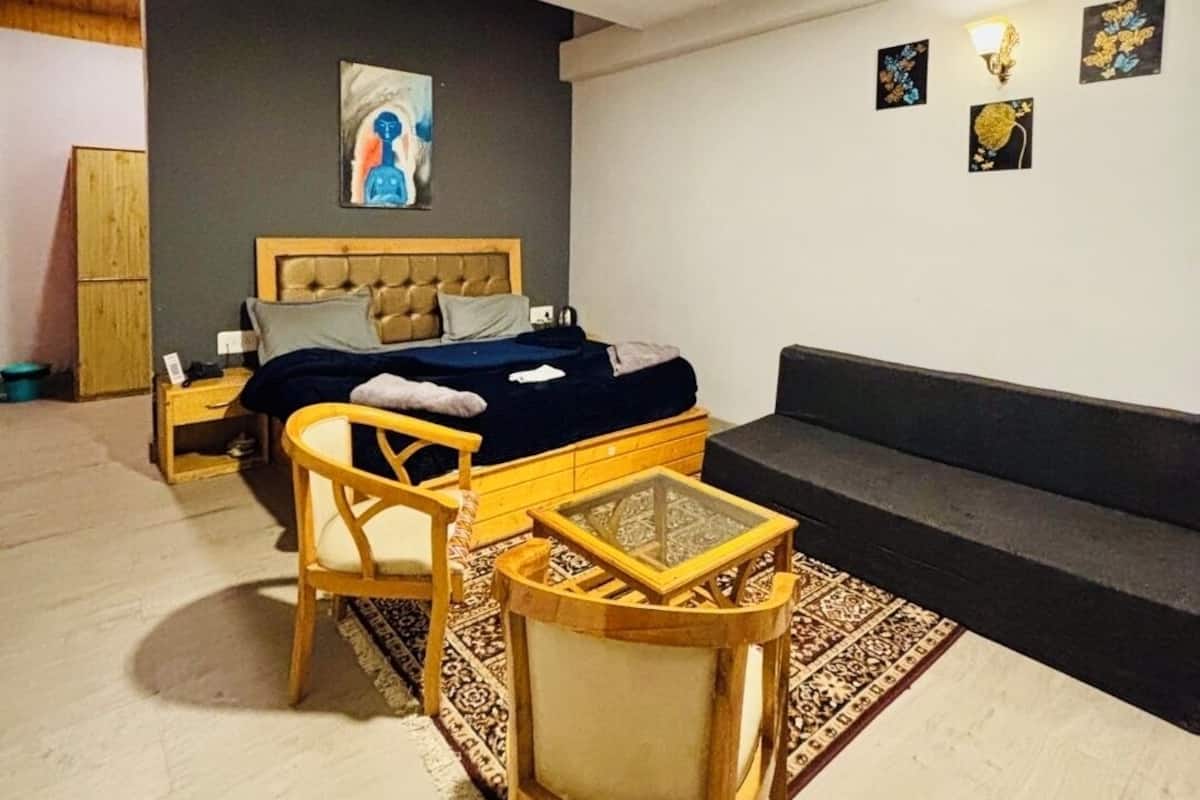 A modern bedroom with a bed, a wooden chair, a glass coffee table, and a sofa.