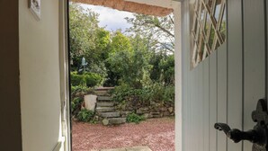 A doorway leading to a garden with a stone staircase, a stone wall, and a thatched roof structure. - Rowantree Cottage (Kelso)