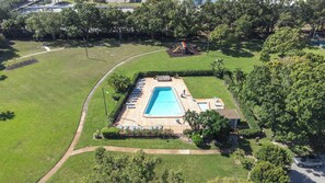 Ett flygbildsbild av en bostadsfastighet med en swimmingpool, solstolar och en liten uteplats.