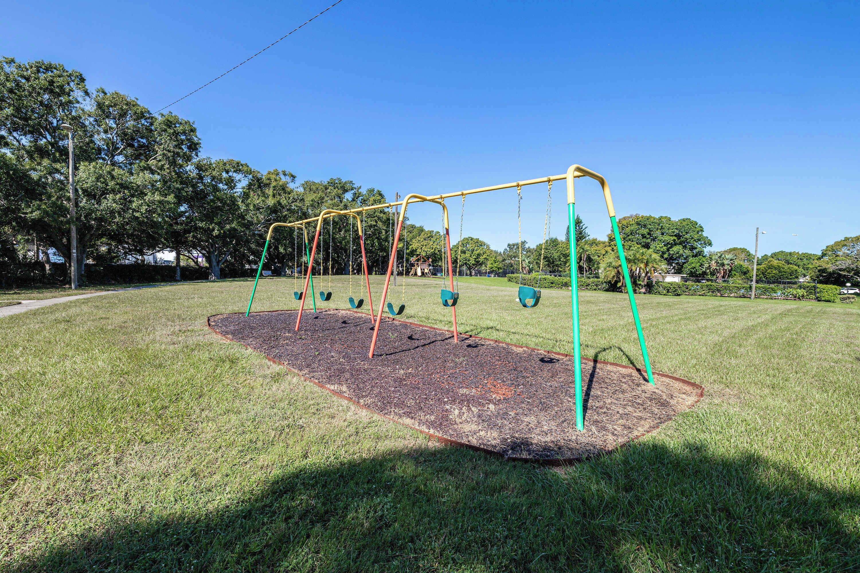 Ein Spielplatz mit Schaukeln und Fallschutzbelag.