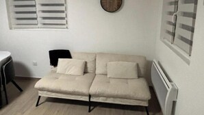 Una habitació petita moblada amb un sofà, una cadira i un radiador.